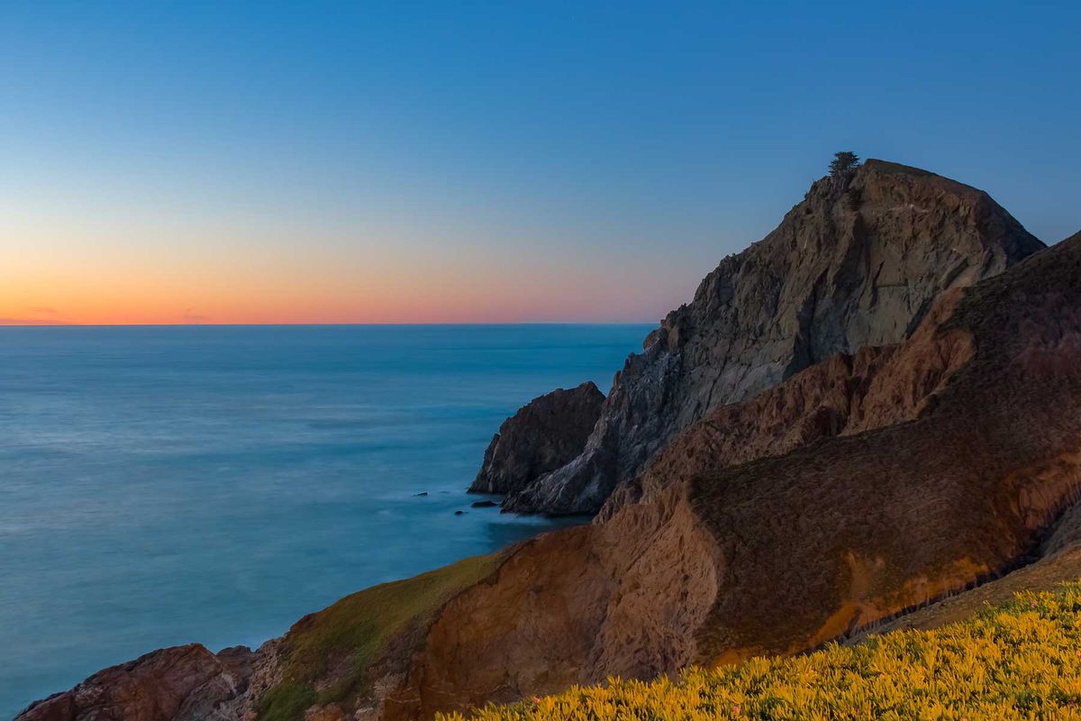 Rugged coastal cliffs by the Devil's Slide trail in California at sunset and silky ocean from long exposure