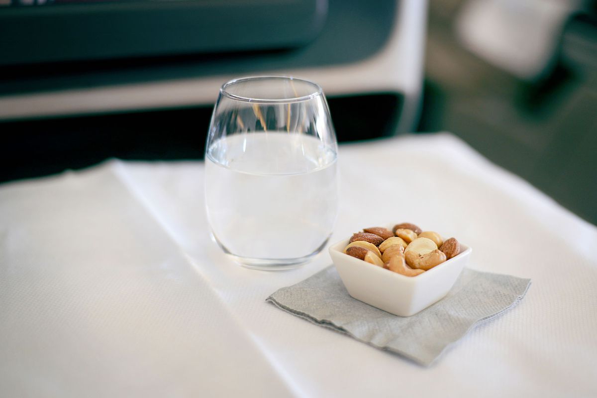 peanuts and a glass of water placed on an airplane seat tray