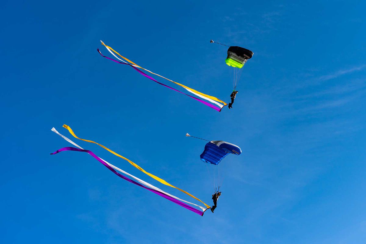Two skydivers with purple, yellow and white streamers