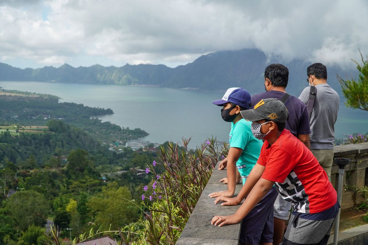 People wearing face masks admire Lake Batur