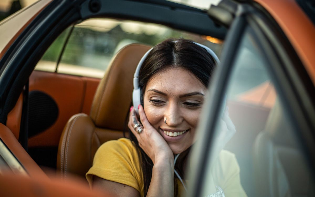Woman listening to music through headphones in car