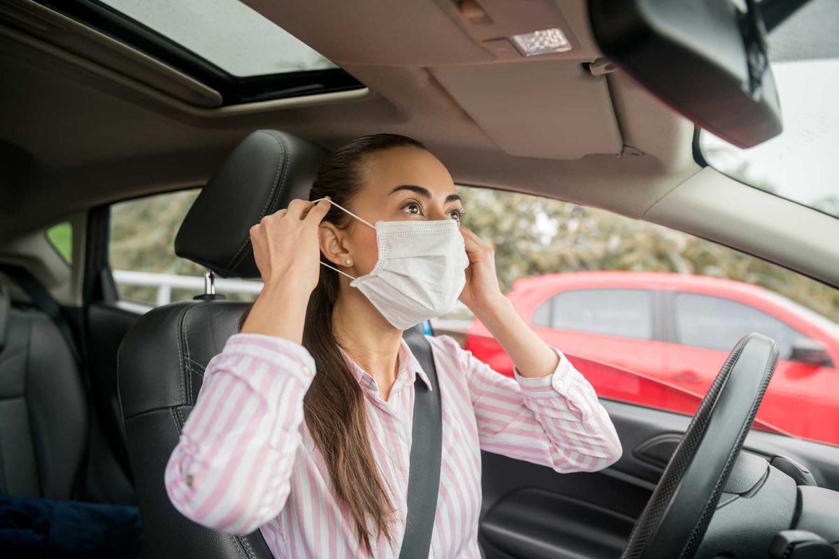 Woman putting on a facemask while in a car