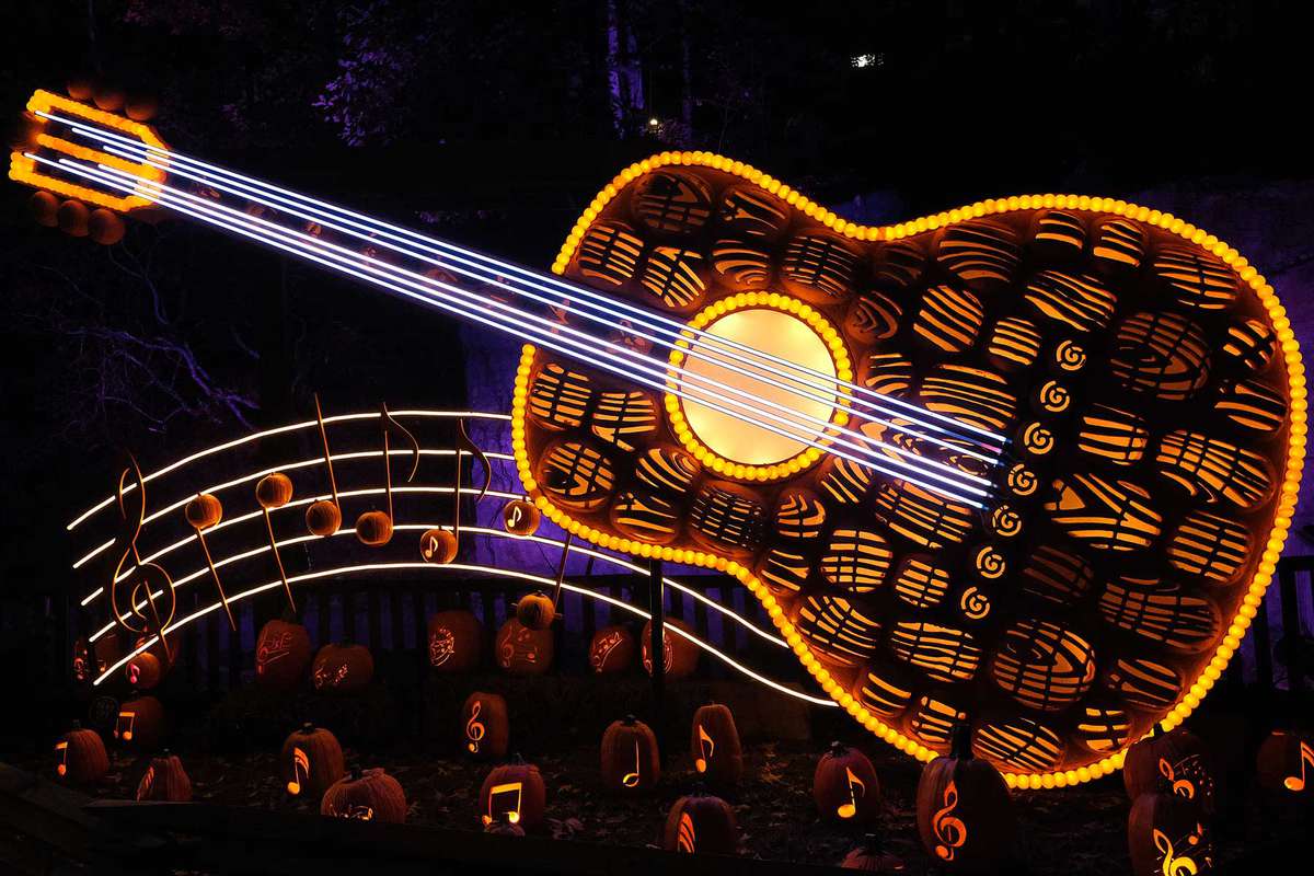 A oversized sculpture of a guitar built of carved pumpkins that glow at night