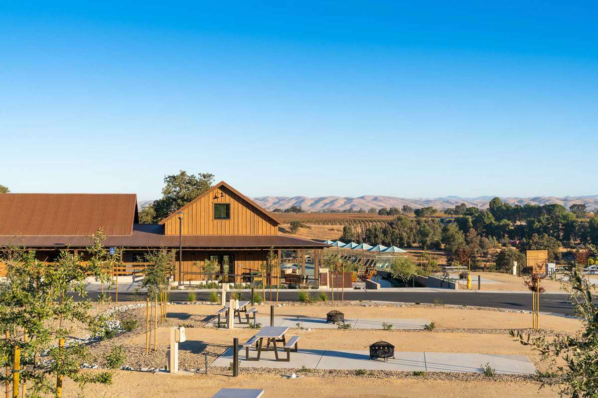 Cava Robles, a luxury RV resort in California shows concrete slabs, fire pits and picnic tables with a beautiful mountain landscape in the distance