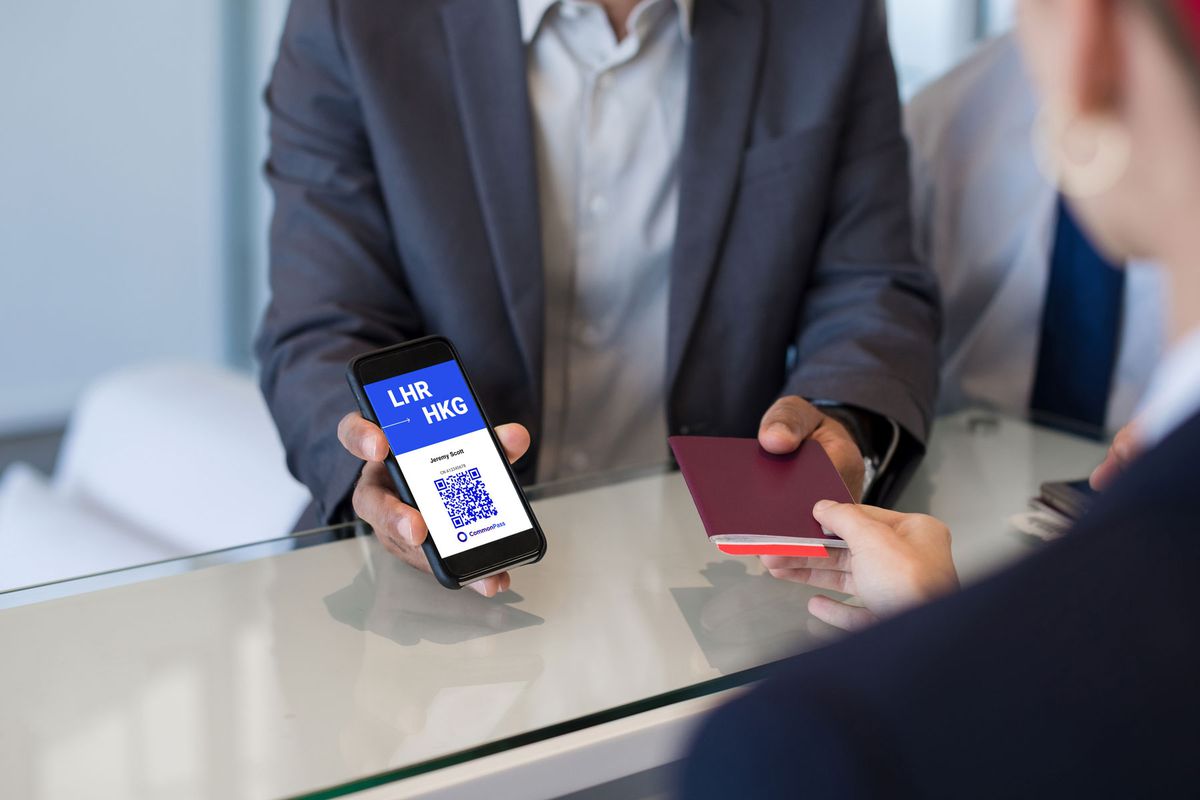 an airport guests holds phone displaying CommonPass App