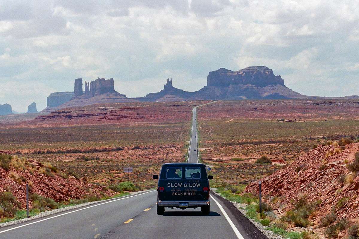 A van with Slow & Low branding on a highway in the desert