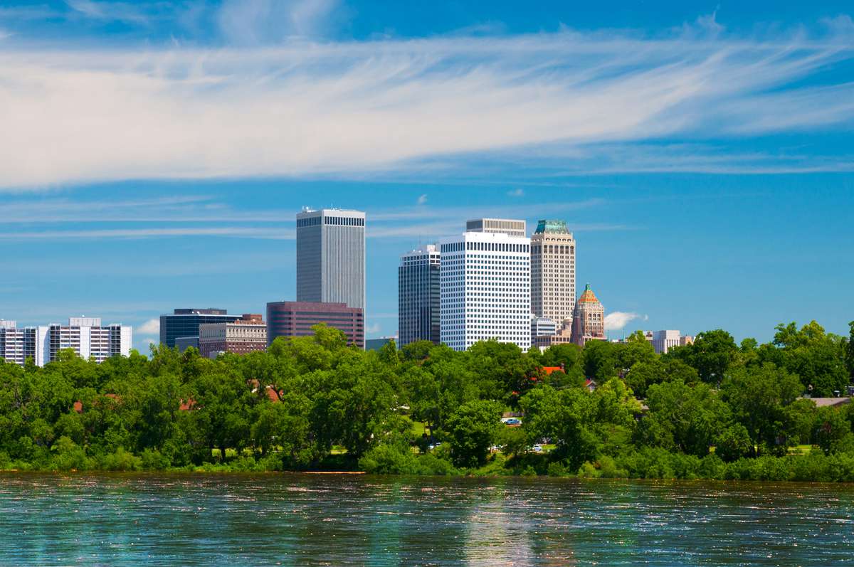 Tulsa downtown skyline with trees and the Arkansas river in the foreground.