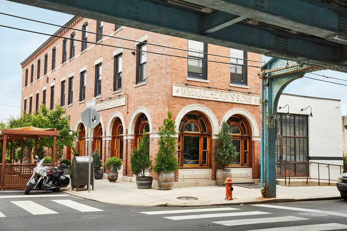 Brick exterior of hotel Wm. Mulherin’s Sons in Philadelphia, with the El train track shown in the foreground