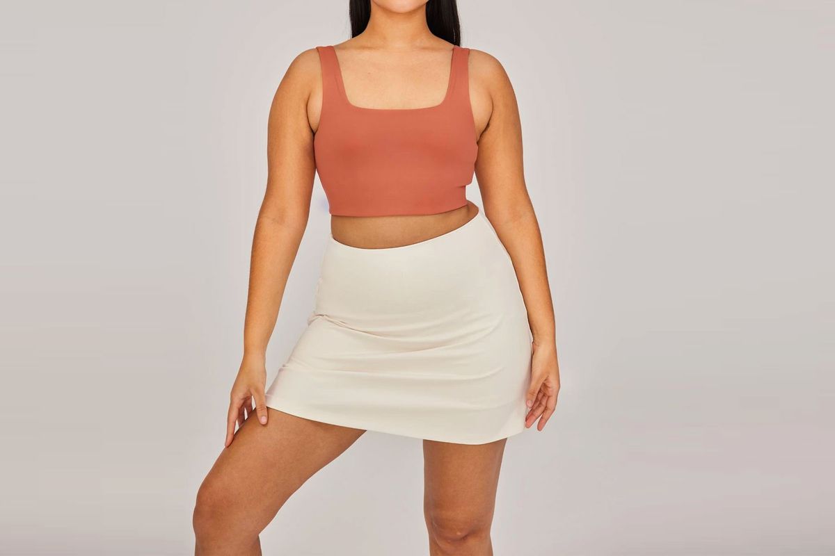 Woman wearing red sports bra and cream colored skort