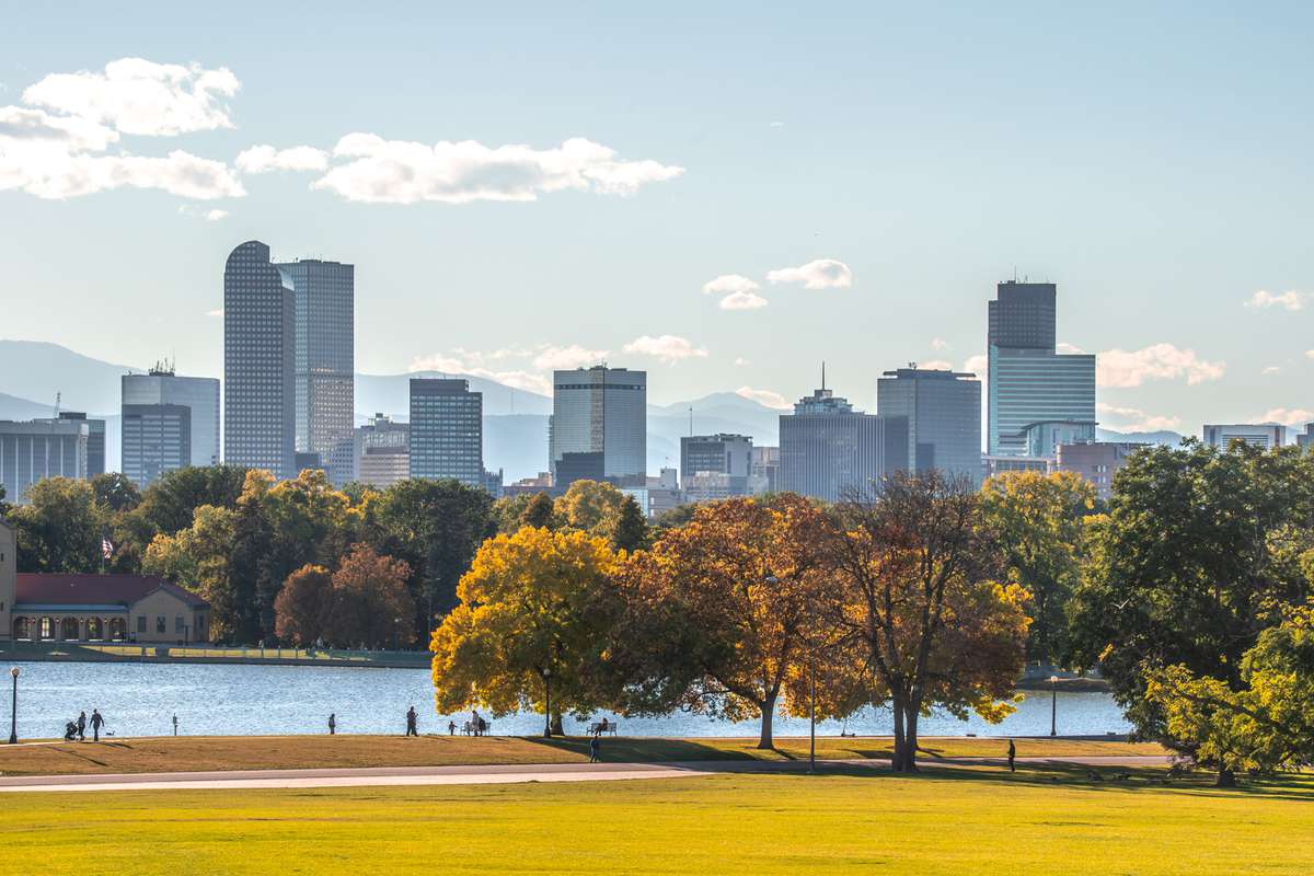Autumn leaves and lake front with skyline and mountains in the distance in Denver, Colorado.