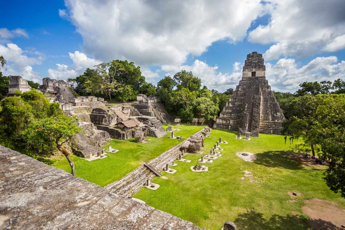 View of majestic mayan ruins with green grass and trees at Tikal National Park in Guatemala near the border of Belize.