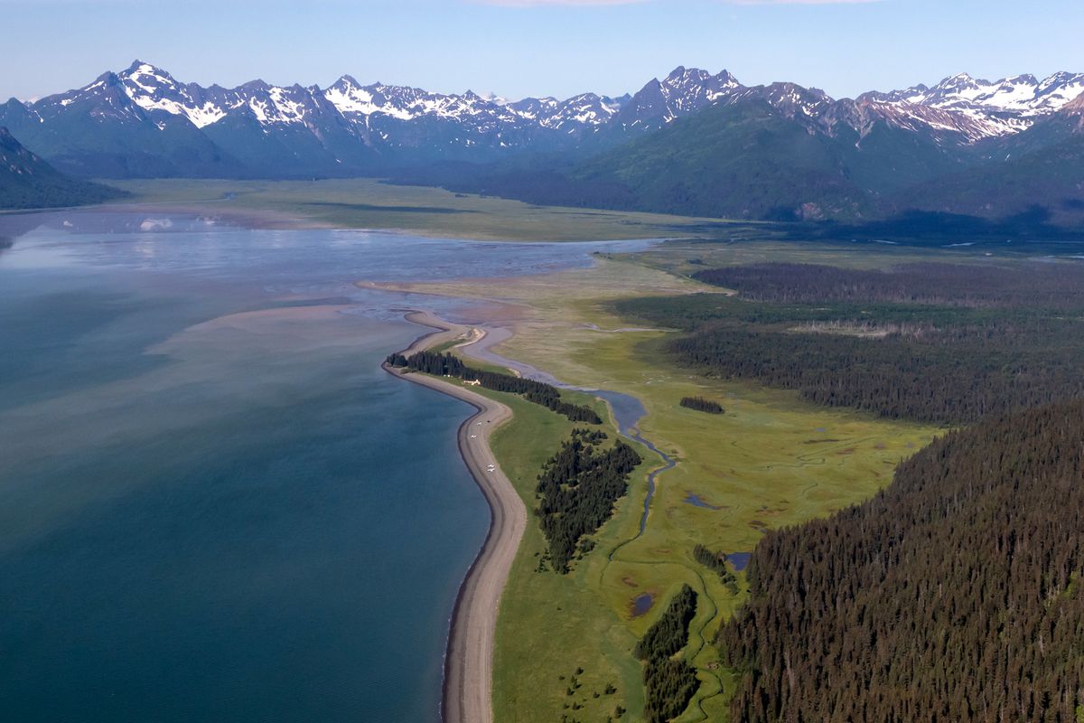 Aerial view of scenic Lake Clark National Park with water and snow capped mountains in the background.