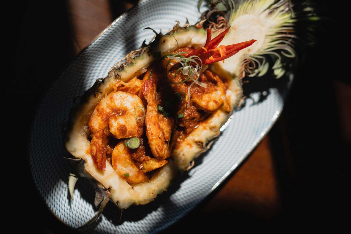 A dish of pineapple and prawns shown in the shadows