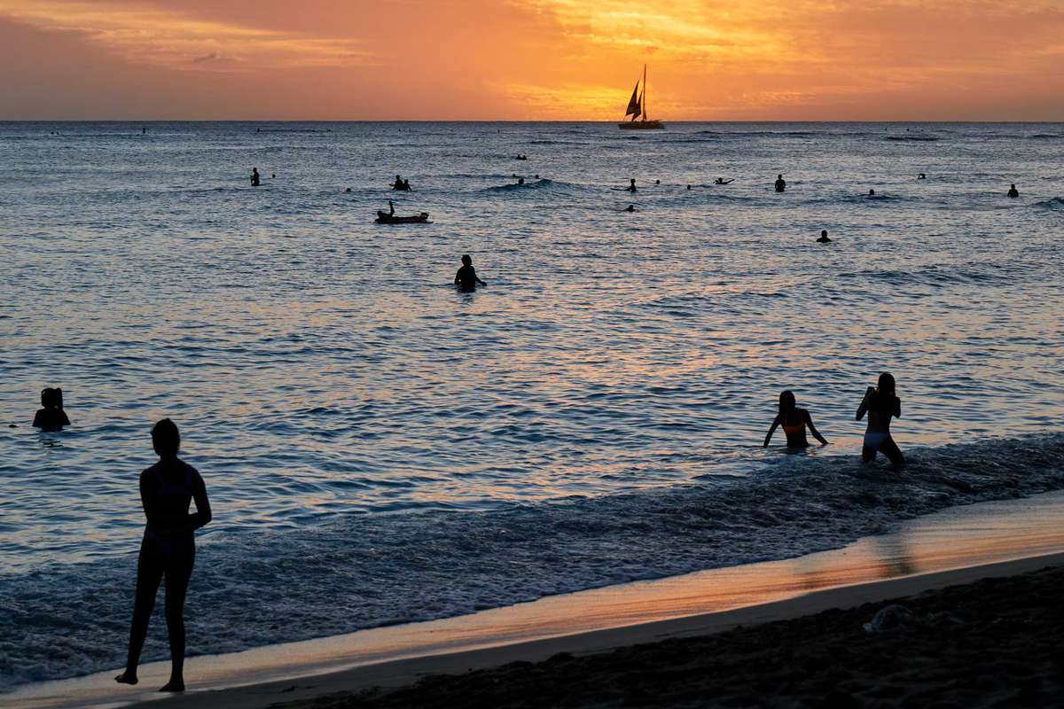People in the water at Waikiki Beach, Hawaii, at sunset