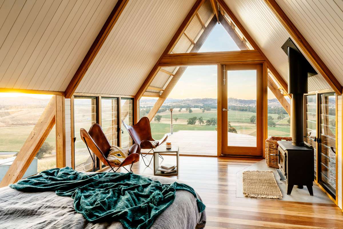 Airbnb with large windows, bed overlooking field and hills
