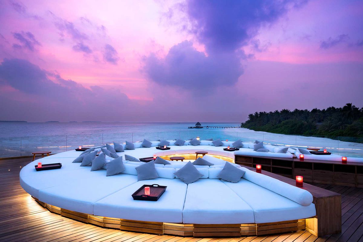 Lounge seating on the desk at Anantara Kihavah Maldives at sunset