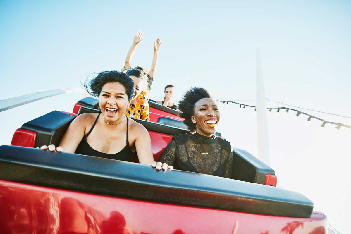 Female friends riding roller coaster at amusement park