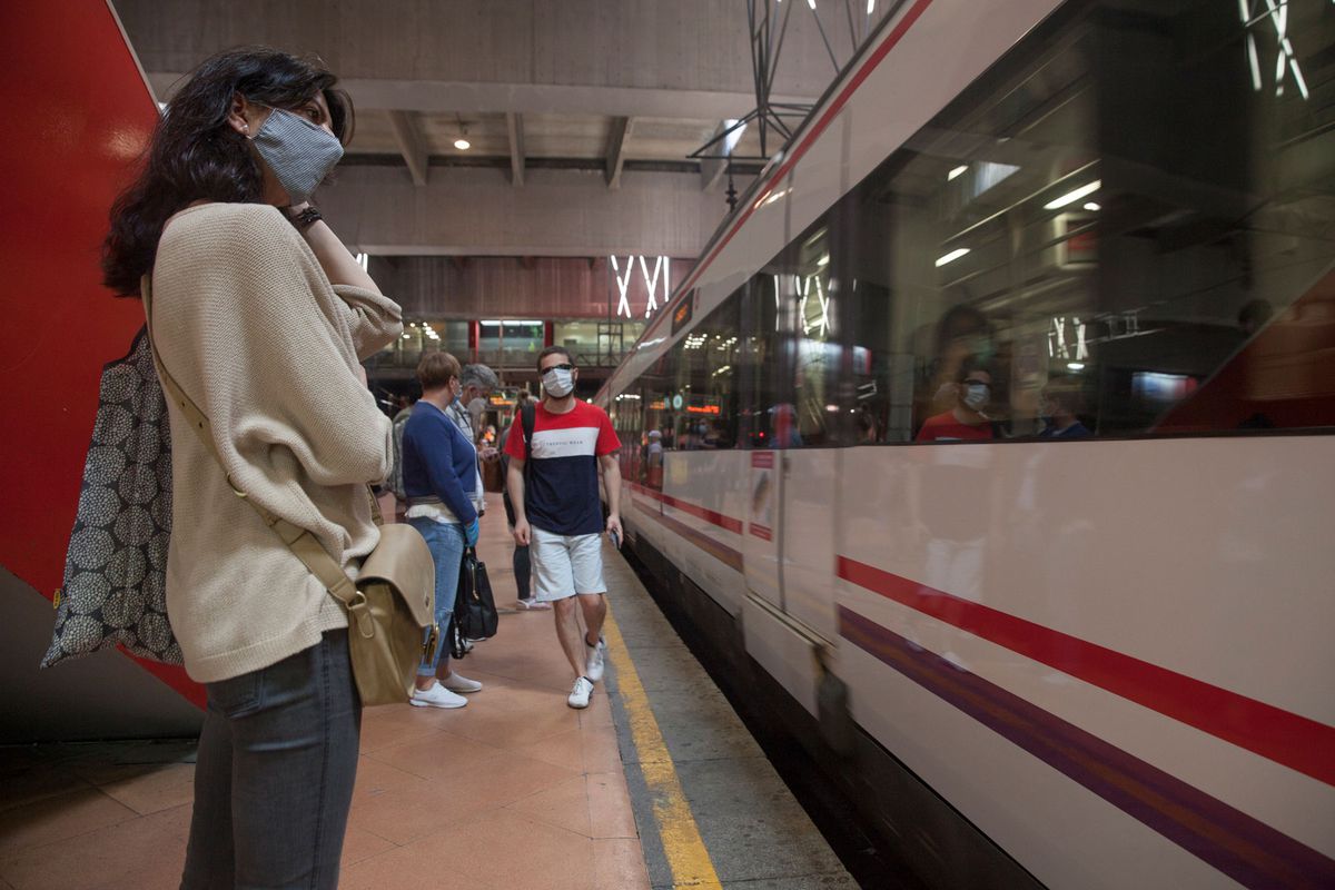 People wearing face masks commute at Atocha train station