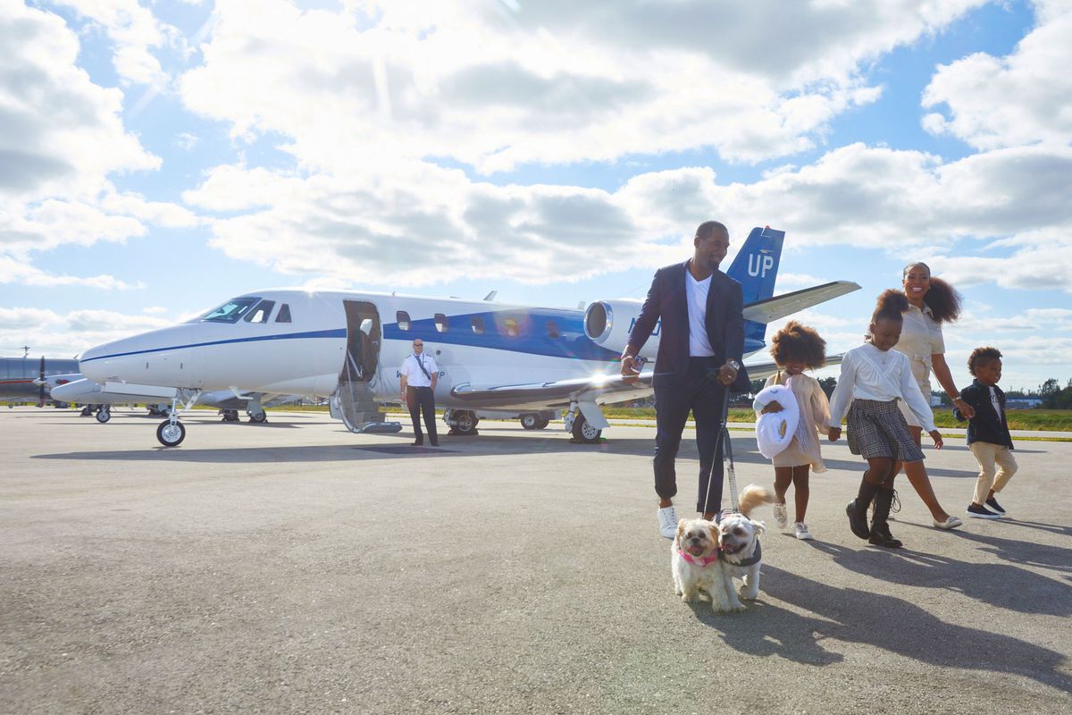 Family with kids and dogs walking off private jet at airport
