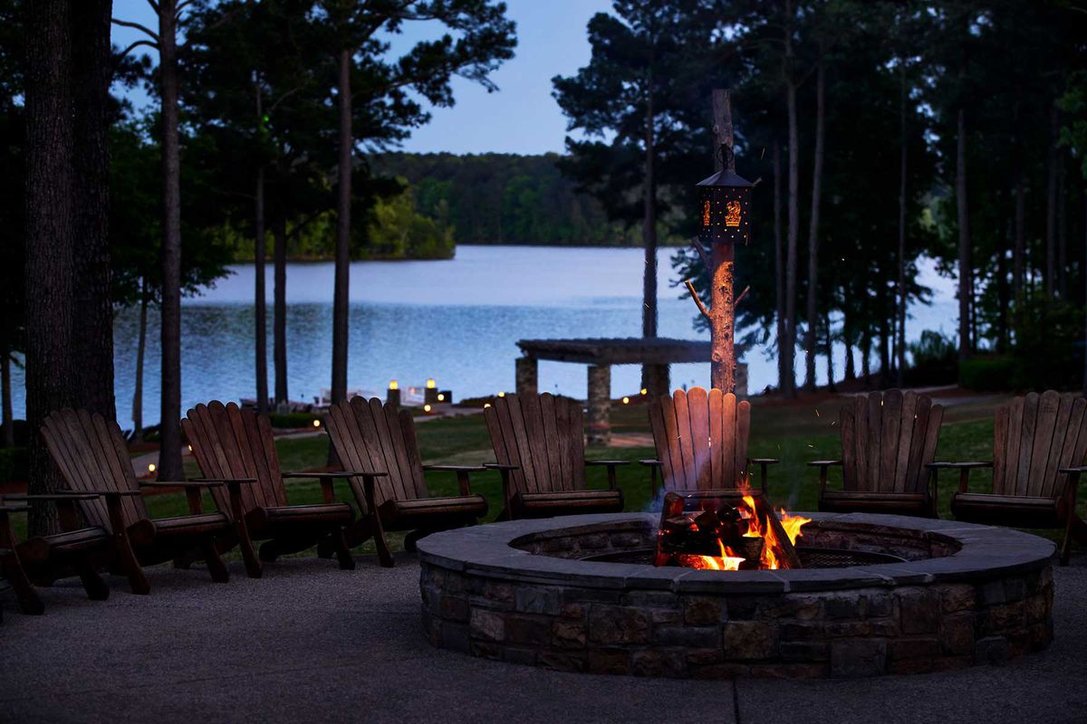 Chairs by a fire in front of a lake