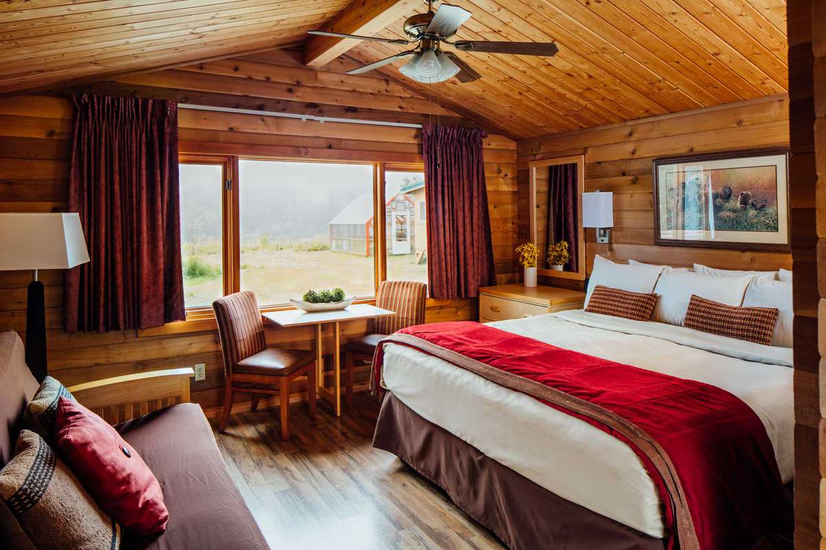 Interior room at Denali Backcountry Lodge showing bed and chair with window view