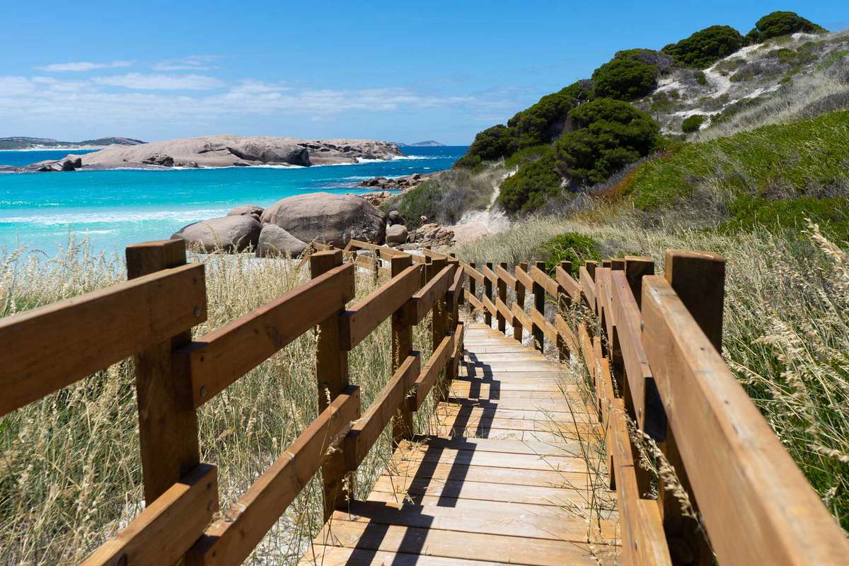 Photo of wooden walkway leading to beach with bright blue sea, Cape Le Grand National Park, Western Australia