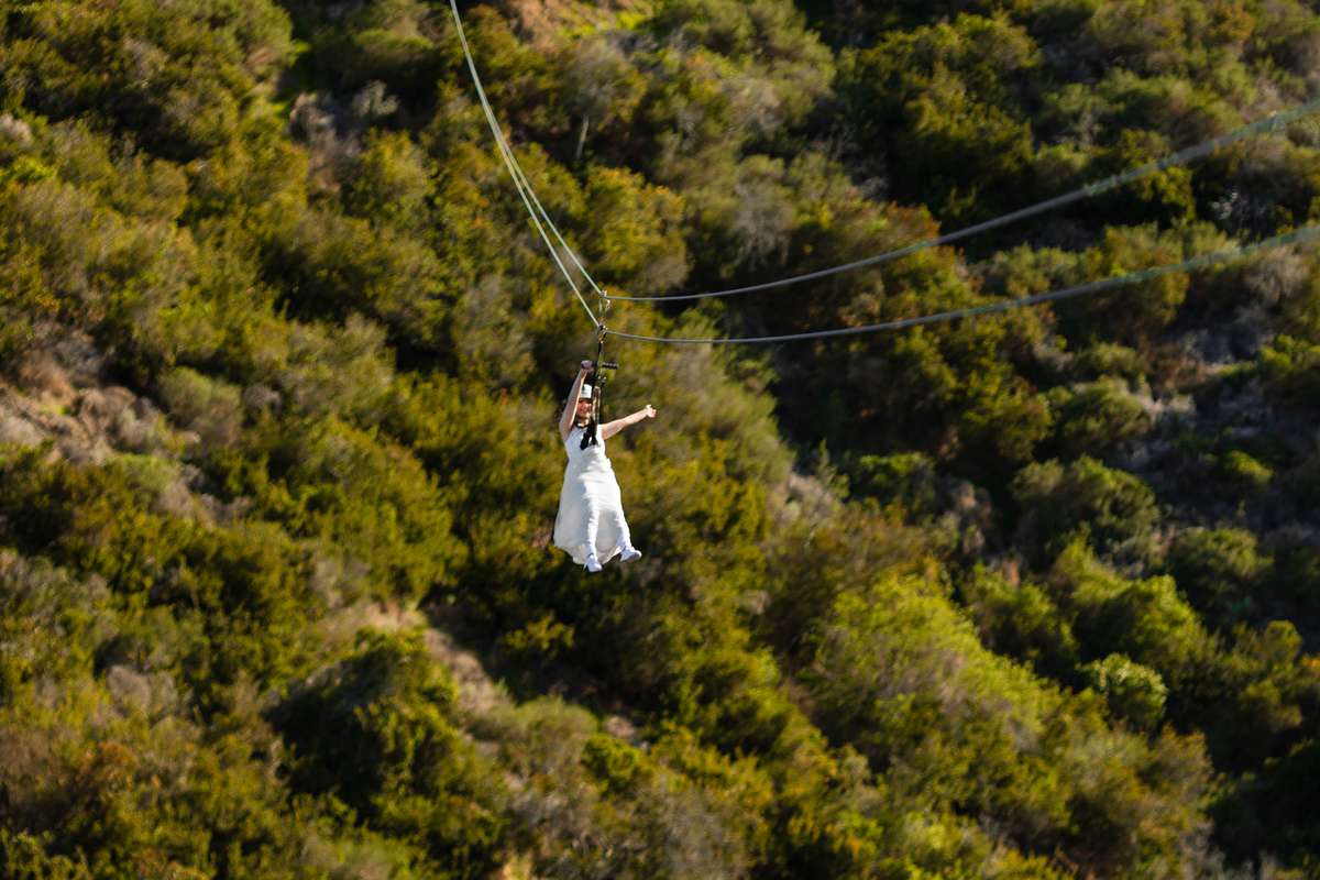 bride in wedding dress zip lining down mountain