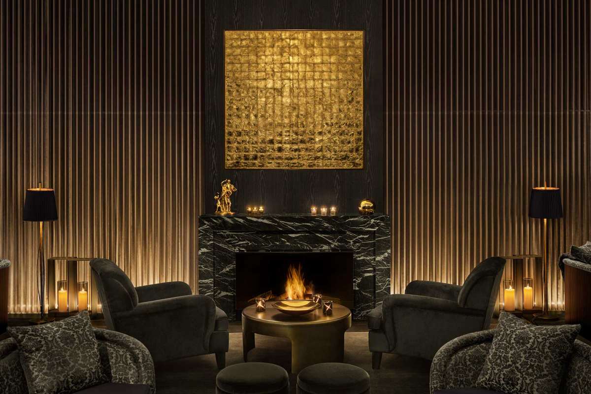 Lobby of The Tokyo EDITION hotel with fireplace and dark hues with gold accents