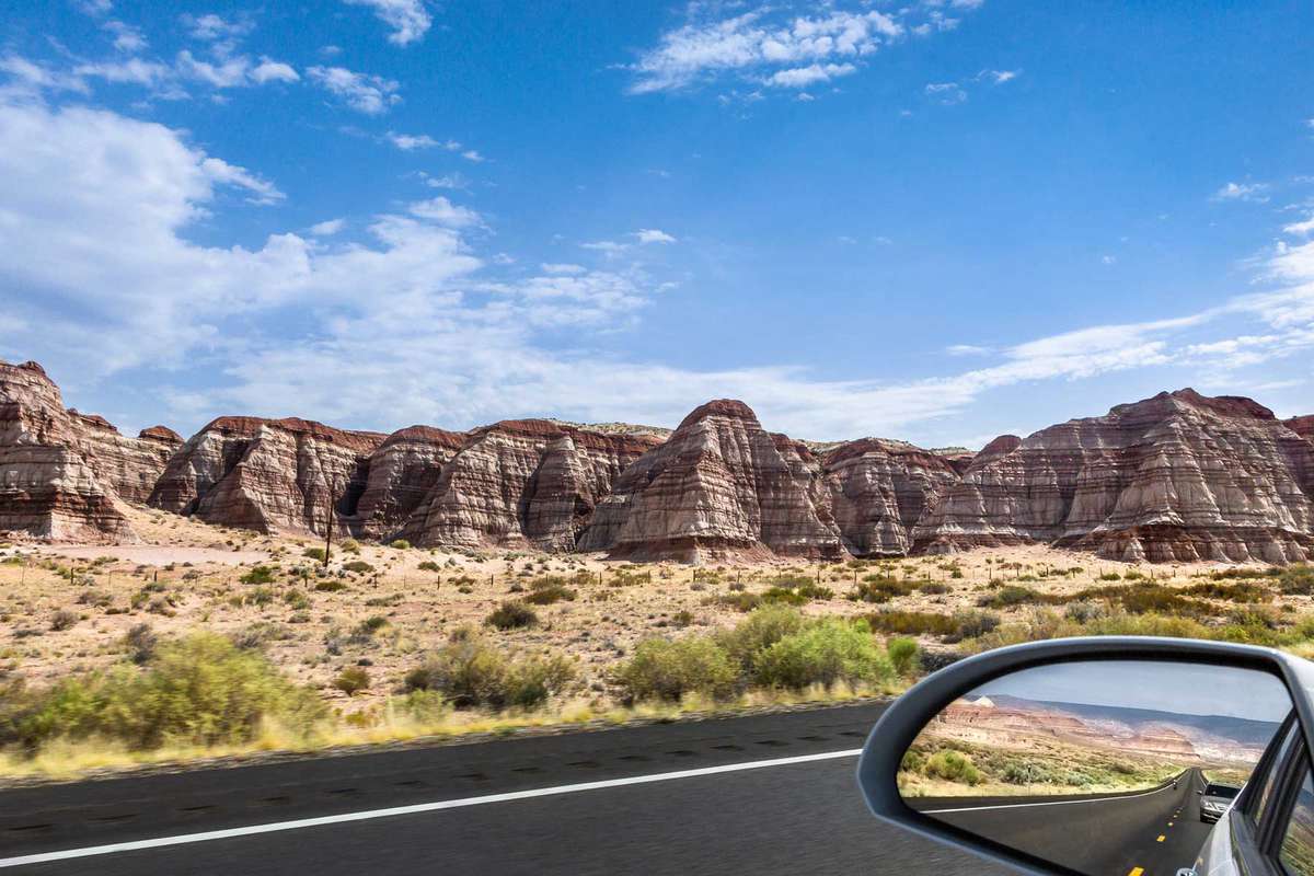 Rock formations along a road in Utah with a car side mirror view
