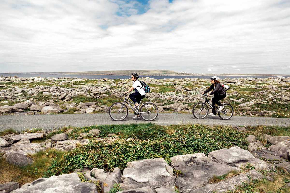 Two cyclists exploring the windswept landscapes of Inis Oírr in Ireland