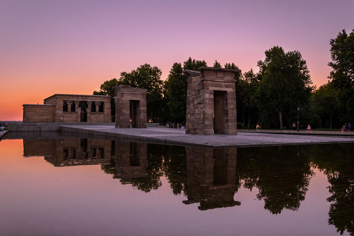 Historic Temple Of Debod Reflection In Pond Against Pink Sky During Sunset