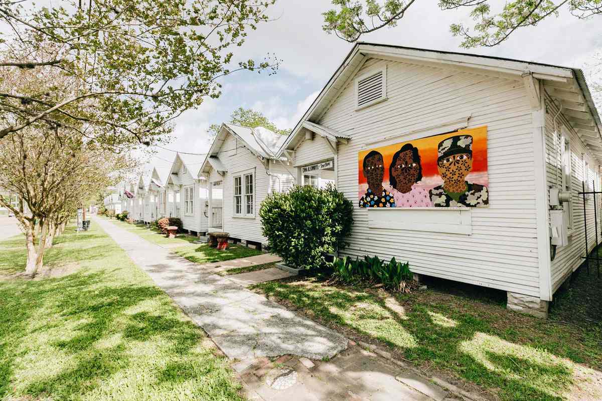 Artist row houses in Houston, TX, with one showing colorful memorial artwork by artist Jasmine Zelaya