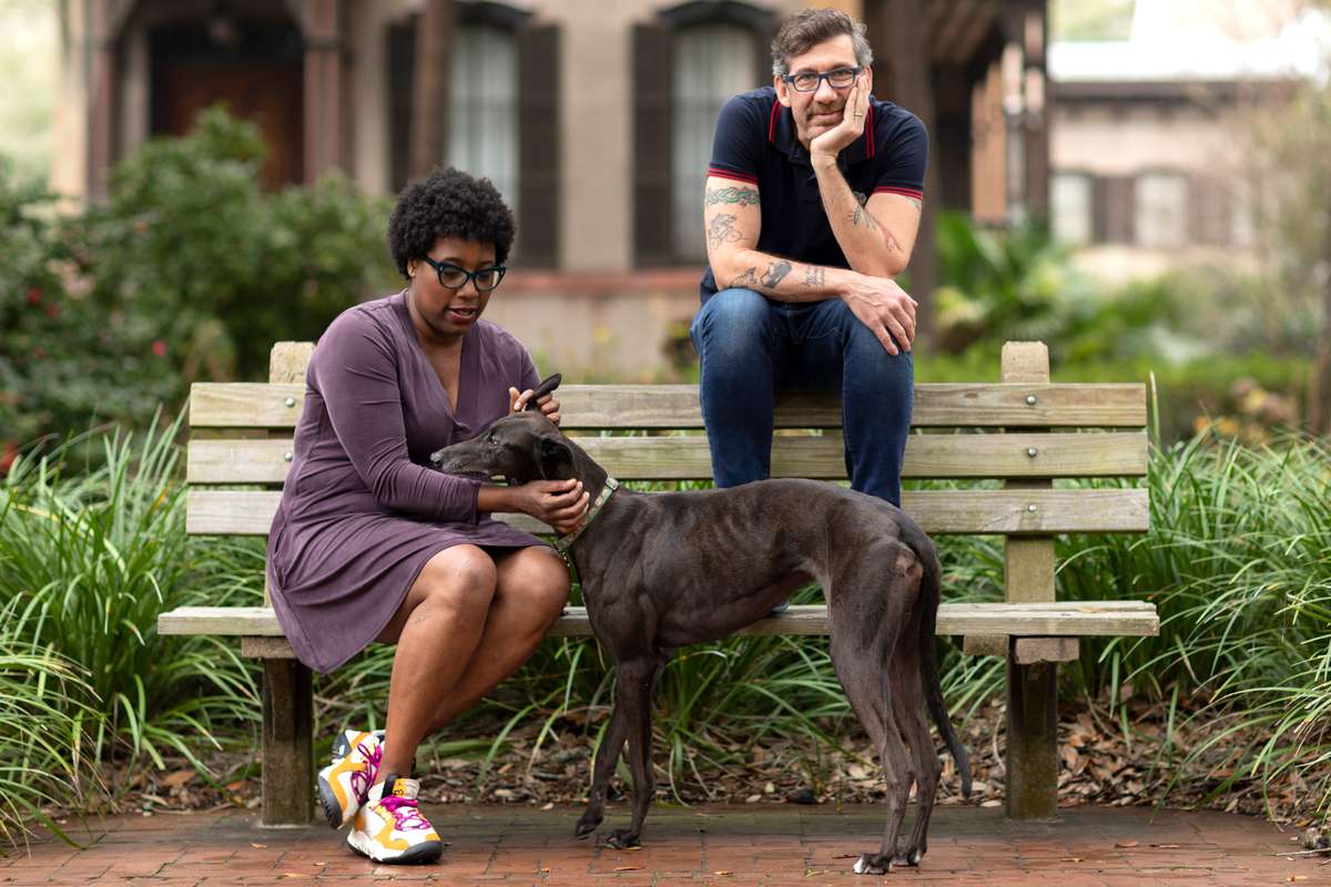 Outdoor portrait with Mashama Bailey and John O. Morisano with a dog on a bench