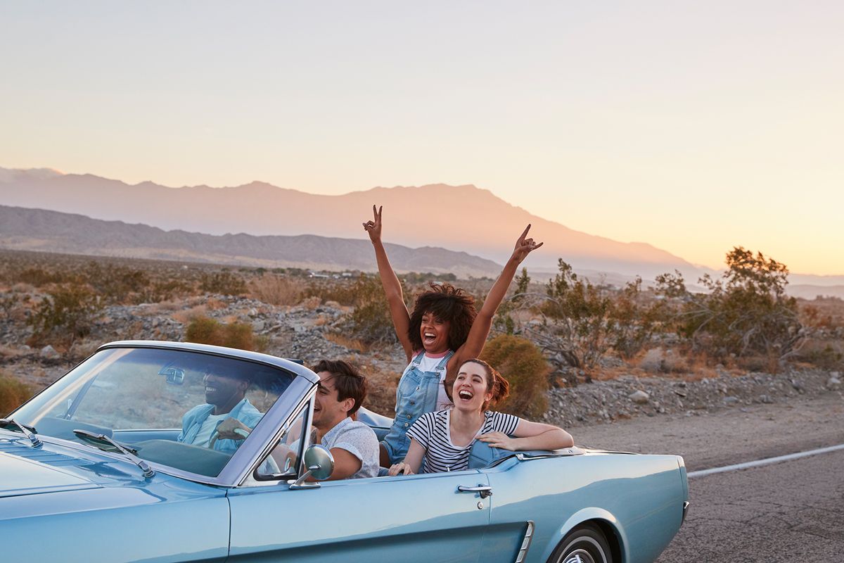 Group Of Friends On Road Trip Driving Classic Convertible Car
