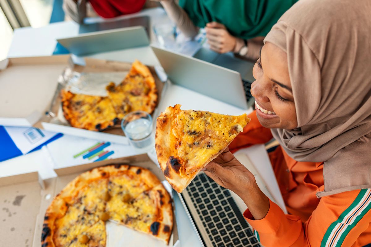 Woman eating a pizza while working