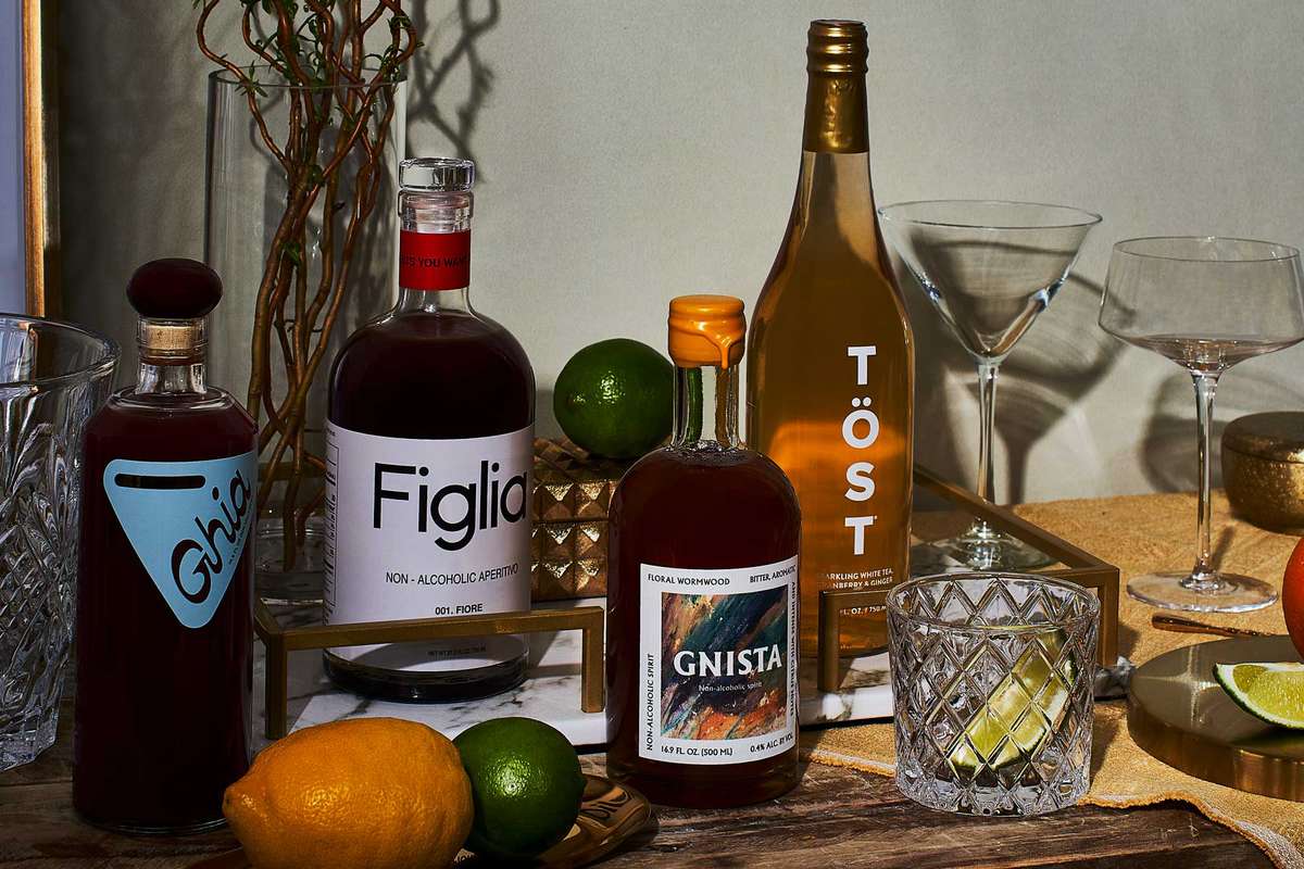 Home bar table showing four bottles of non-alcoholic spirits, glasses, a lemon, and limes