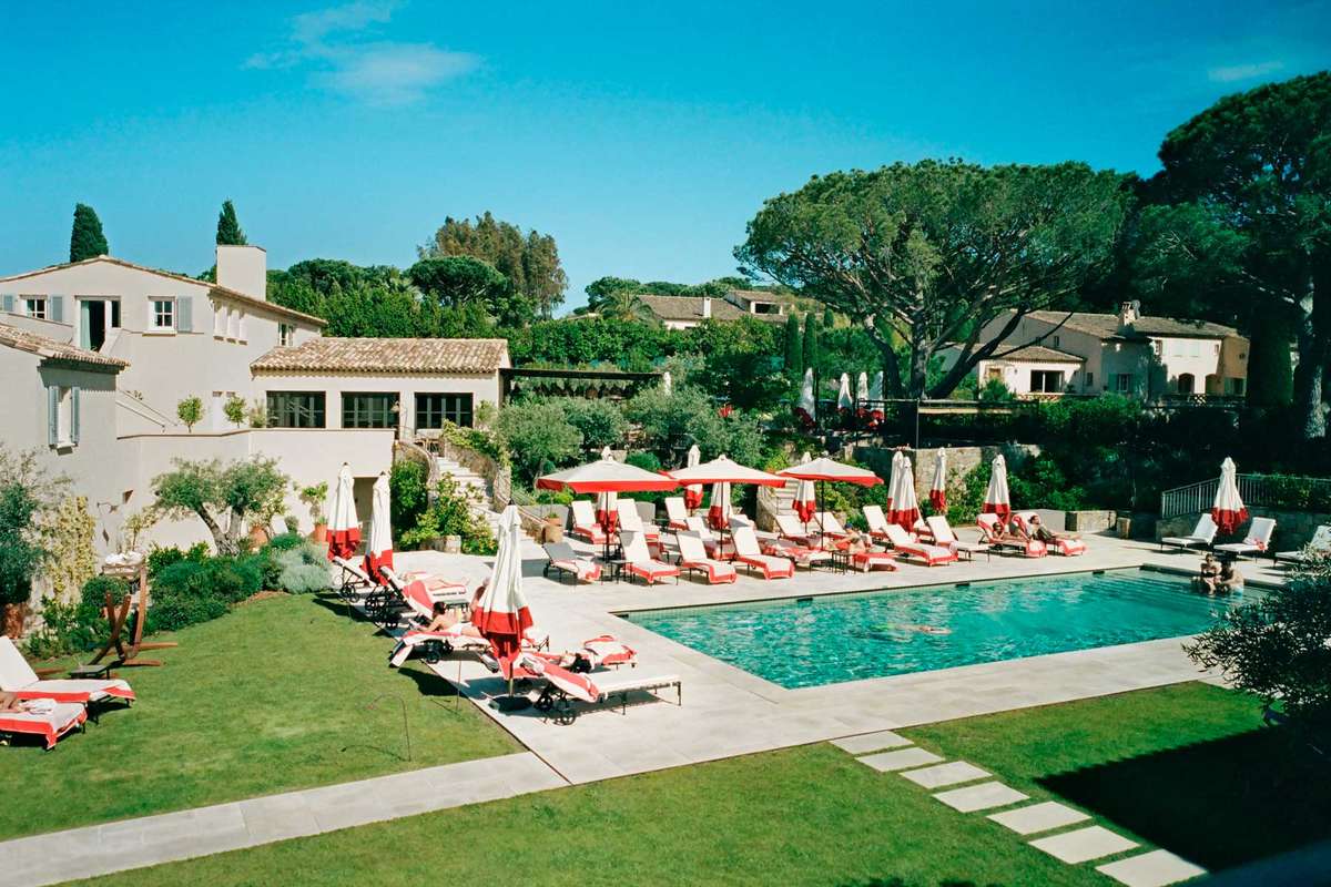 A hotel pool in St Tropez surrounded by red and white deck chairs
