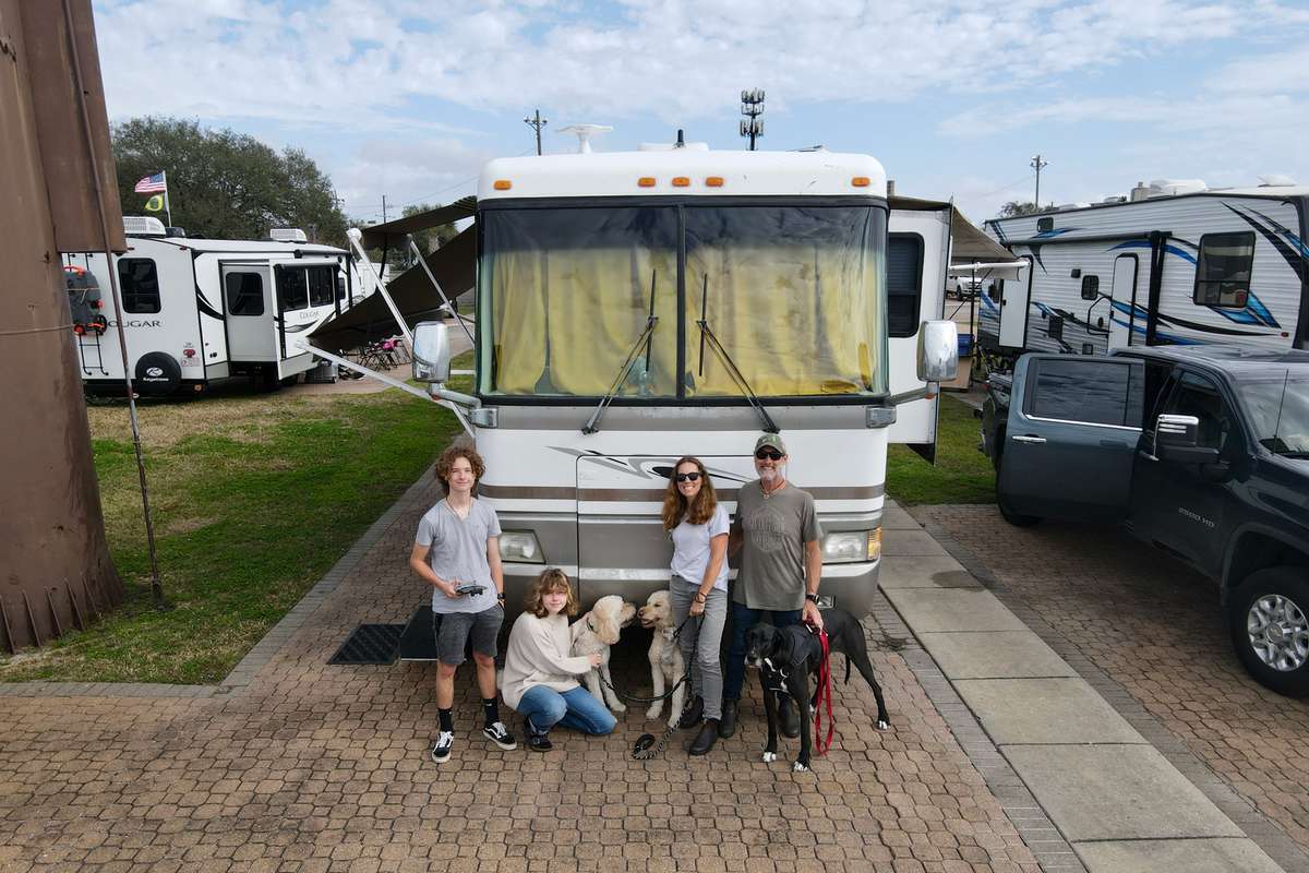 Photo of the Gamble Family in front of their RV Trailer with the three dogs