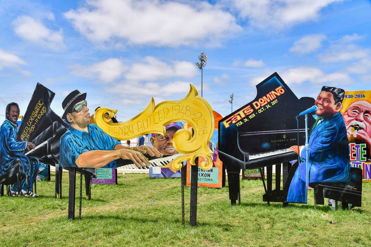 Large painted cutouts of famous jazz musicians sit in field during New Orleans Jazz Festival