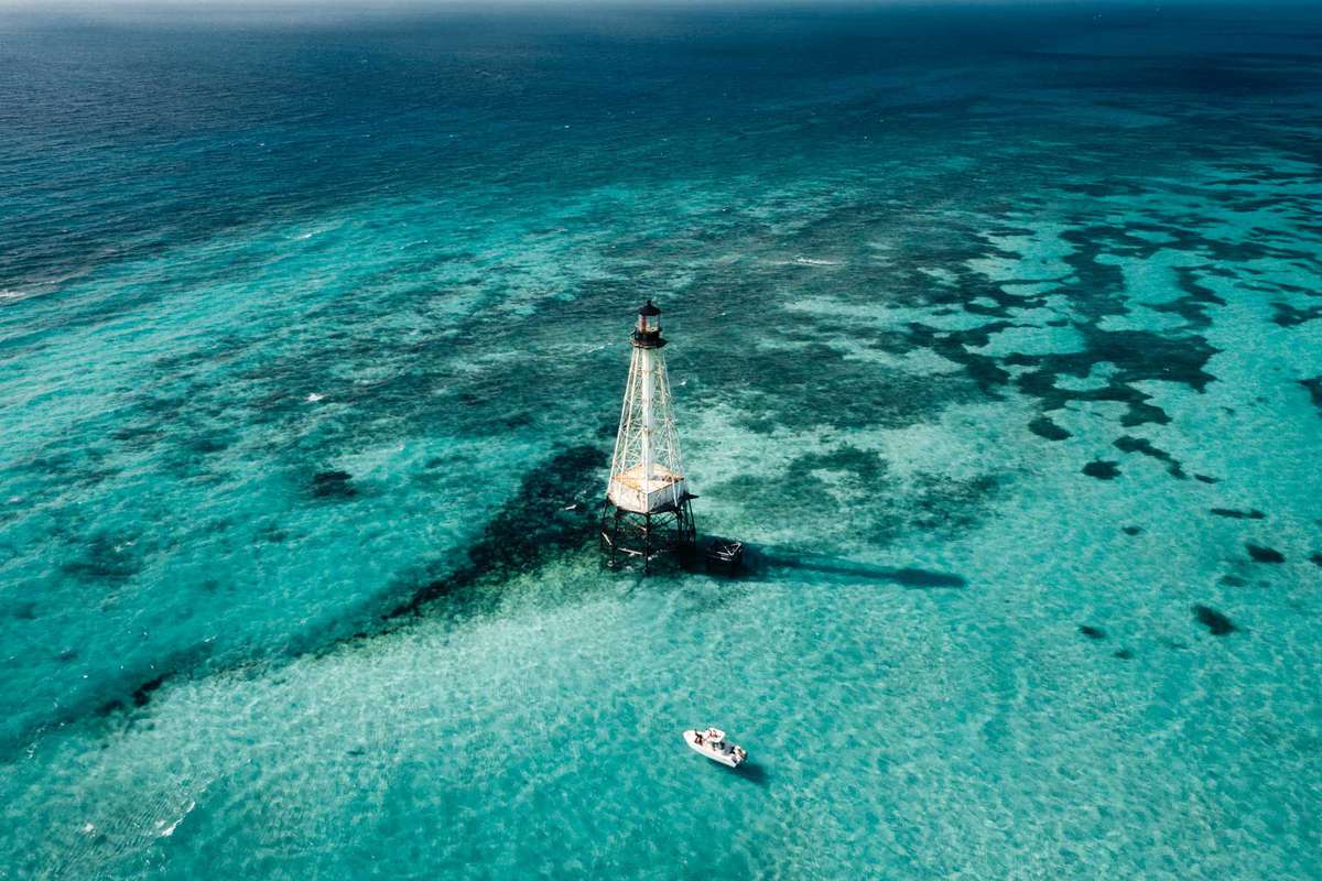 A boat in the clear water near the lighthouse at Alligator Reed, in the Florida Keys