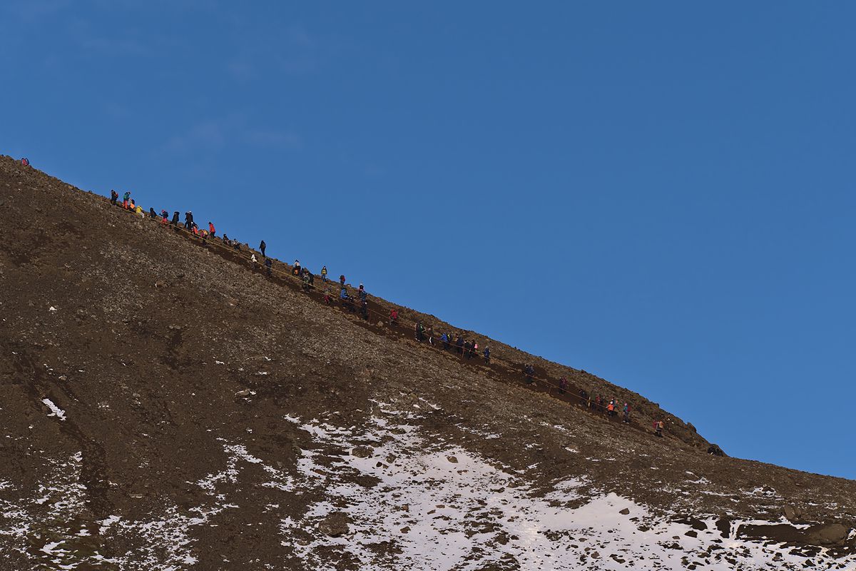 People climbing up a rocky hill on the hiking path to a recently erupted volcano near Fagradalsfjall mountain in Geldingadalir valley in southwestern Iceland on Reykjanes peninsula.