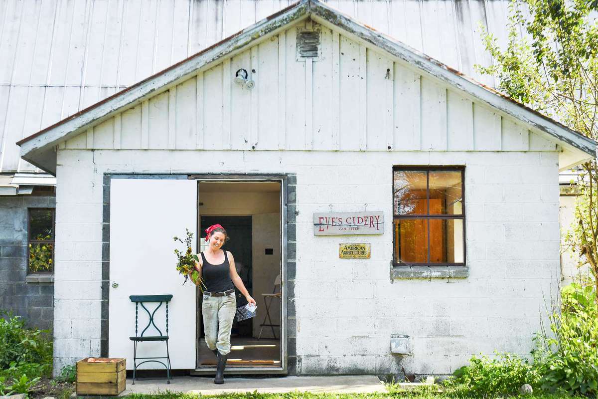 A woman walking out of a cider house in New York
