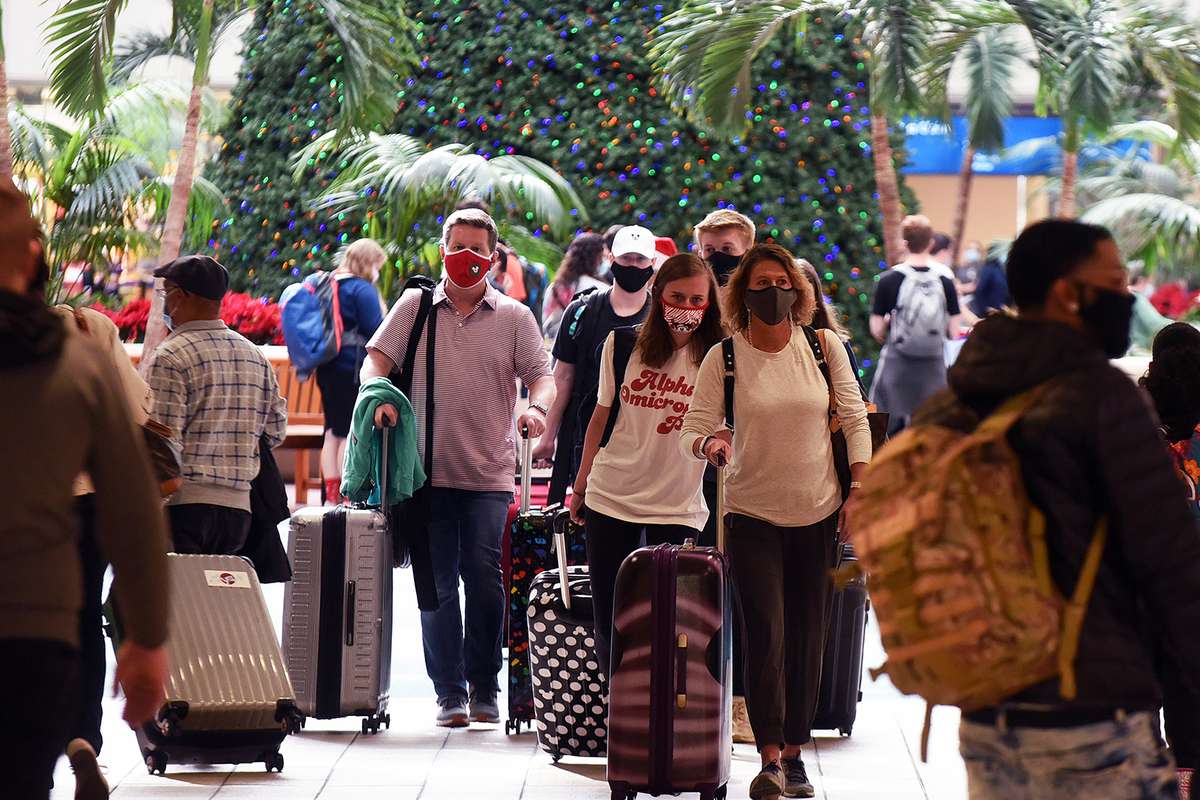 Travelers wearing face masks arrive at Orlando International Airport on the day before Christmas