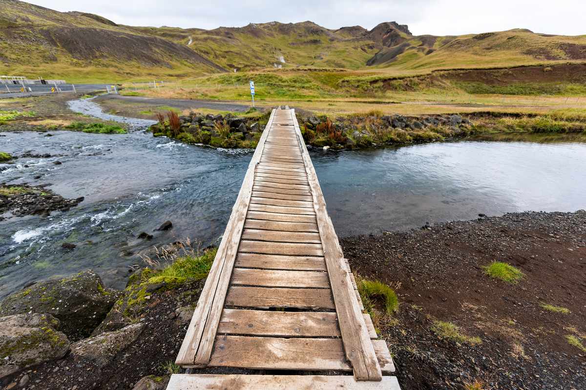 Hveragerdi Hot Springs trail in Reykjadalur, during autumn summer morning day in south Iceland, golden circle, rocks and wooden bridge crossing river steam