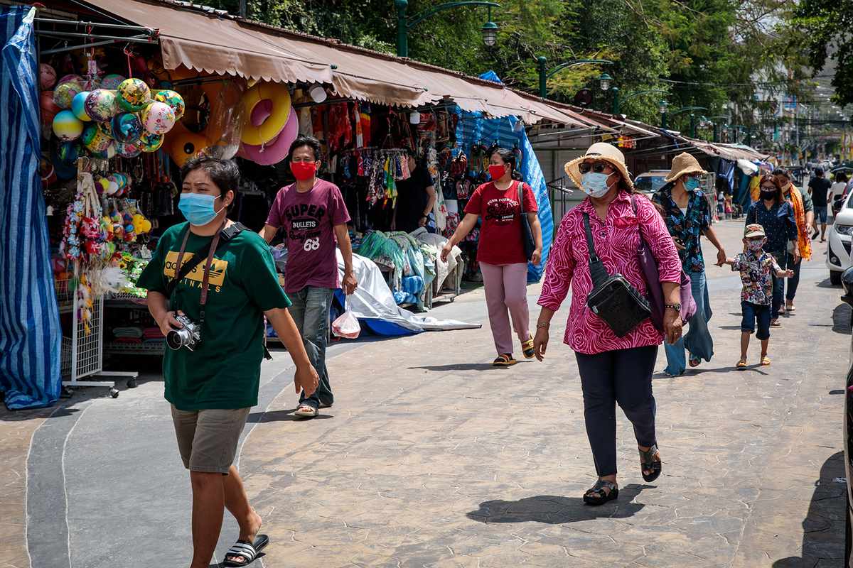 Visitors wearing face masks, amid concerns over the spread of the COVID-19 coronavirus, walk along street shops in Hua Hin beach in Thailand