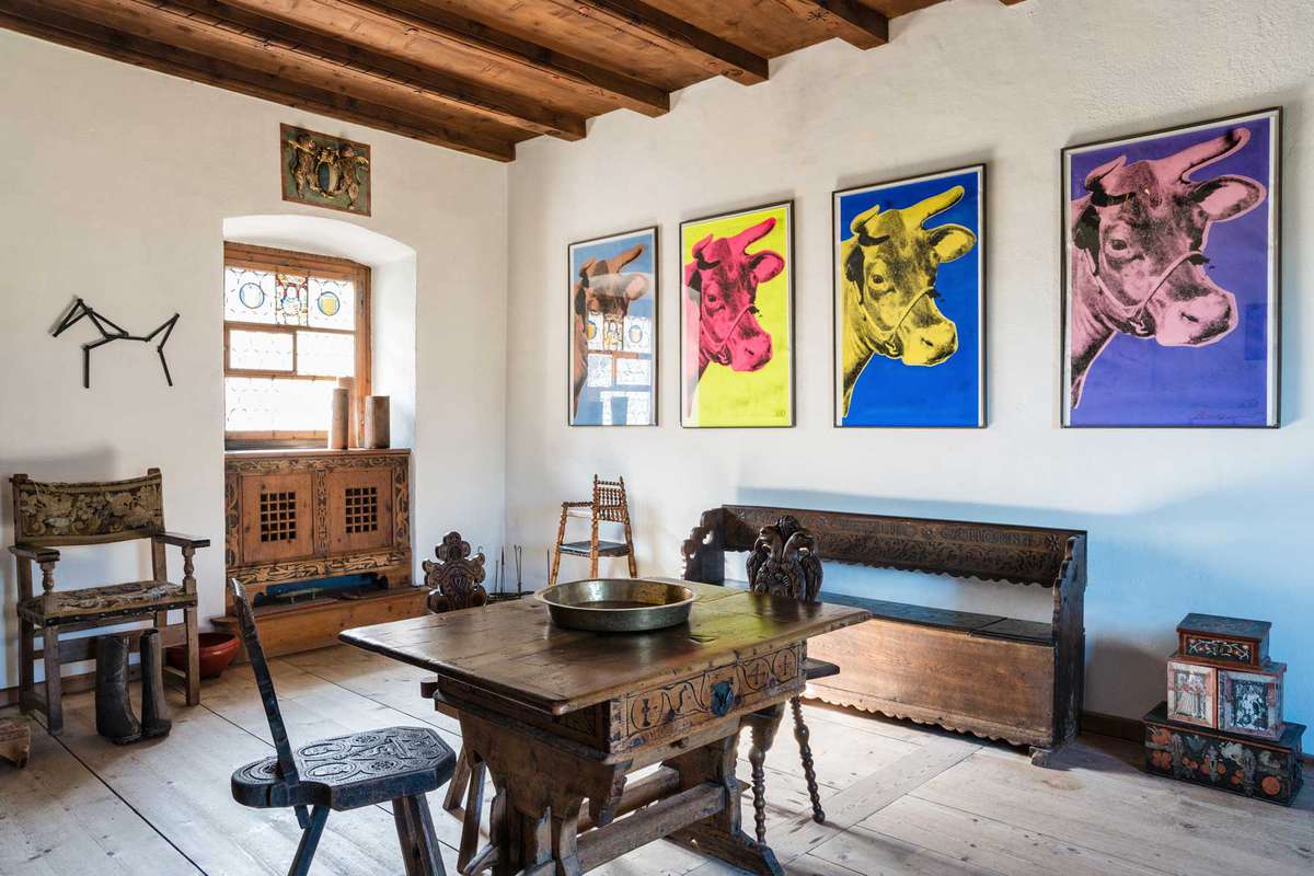Colorful art by Andy Warhol hangs on the wall of a traditional Swiss castle