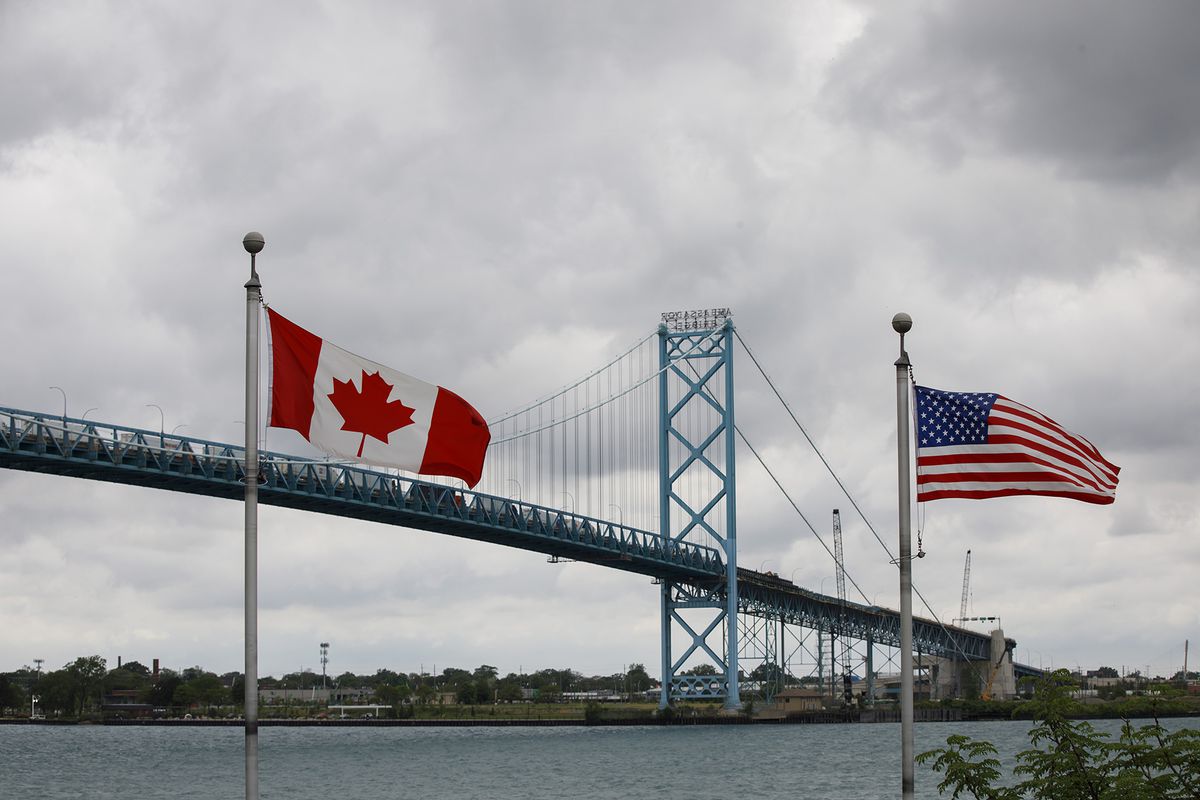 Canadian and American flags fly near the base of the Ambassador Bridge connecting Canada to the U.S. in Windsor, Ontario, Canada,