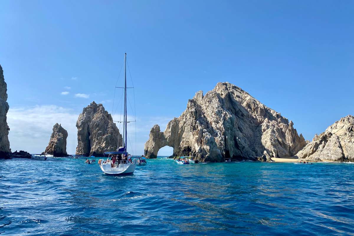 Bright blue skies and water on a sunny day showing the rock formations and archway in Cabo