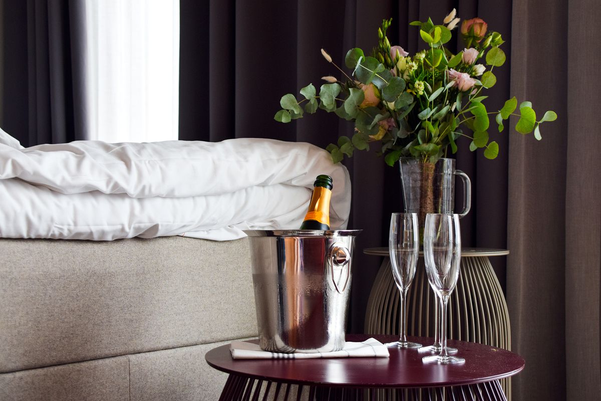Romantic setting in the bedroom with champagne and fresh flowers in a hotel room