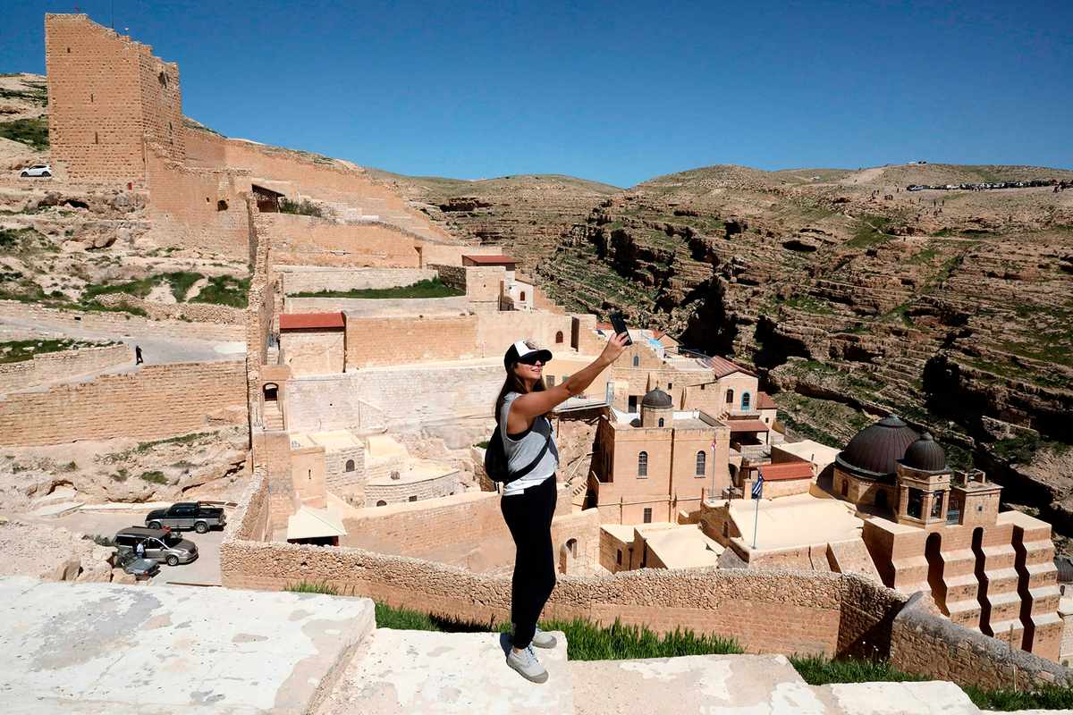 A tourist takes a 'selfie' against a view of the Greek Orthodox monastery of Saint Sabbas (Mar Saba), overlooking the Kidron valley, south of the West Bank biblical town of Bethlehem